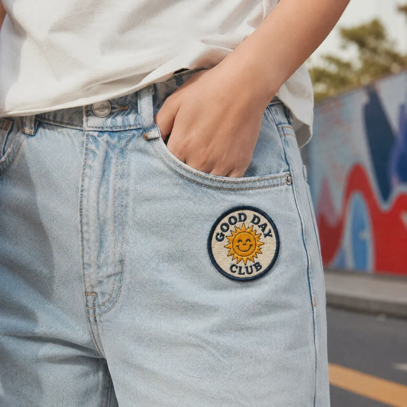 Round Good Day Club chenille sun patch on light denim jeans