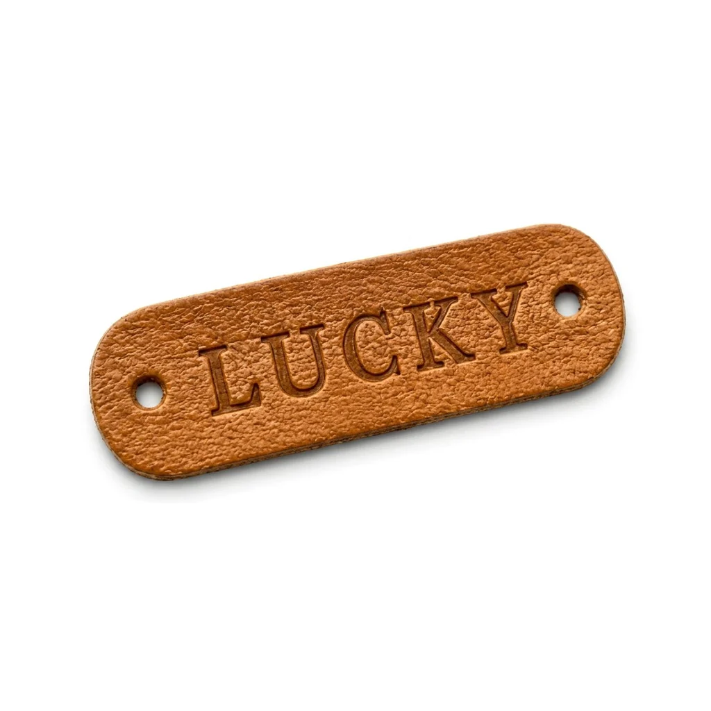 Tan leather logo tag with two stitch holes and debossed lettering