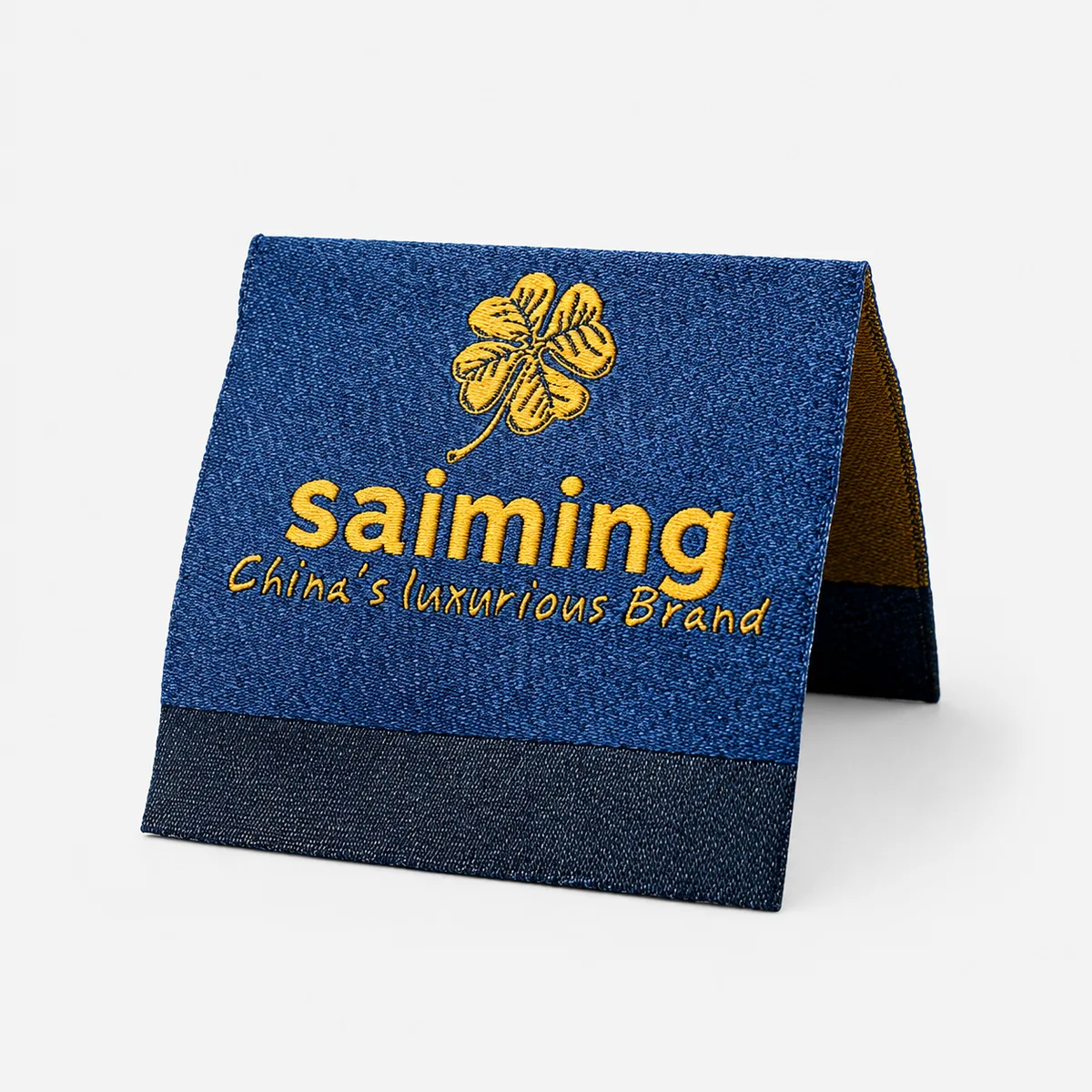 Custom woven saiming denim-look folded brand label with a gold clover