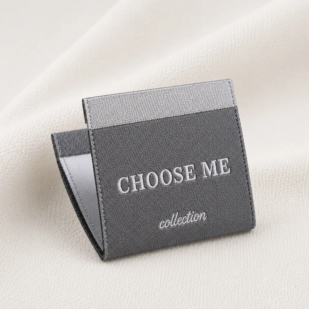 Grey woven Choose Me collection brand label draped on fabric